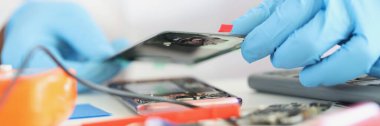 Bozuk cep telefonunu tamir etmek, telefon kılıfı takmak, eldiven tamirciliği. Aletlerle dolu bir işyeri. Tamir servisi, tamir, kullanışlı konsept