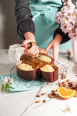 Kolombiya - geleneksel İtalyan paskalya güvercini pastası, fındık bazlı jöle ile dekore etme süreci, badem serpiştirme, kadın el çırpma.