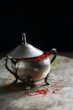 Klasik cupronickel kaplamalı Saffron baharatı metal arka planda, koyu renkli fotoğraf, açık diyafram.