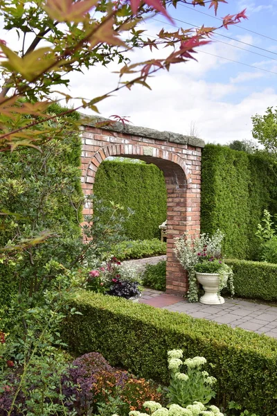 Show garden, green garden interiors surrounded by a thuja hedge, flower pots and low cut edges.