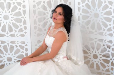 Parlak bir odada, beyaz gelinlik içinde bir gelin.