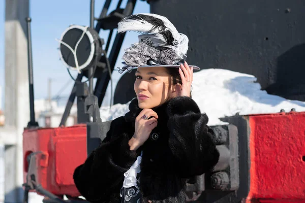 一个穿得像19世纪贵妇的女孩在蒸汽机车旁 俄罗斯冬季 — 图库照片