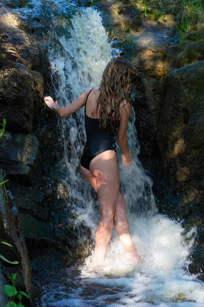 穿着黑色泳衣的女孩在高山瀑布中 — 图库照片
