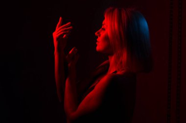 Sarışın bir kızın portresi. Kırmızı ve mavi ışıklı bir odada.