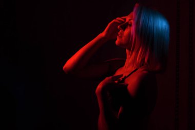 Sarışın bir kızın portresi. Kırmızı ve mavi ışıklı bir odada.