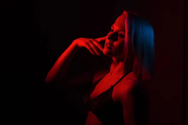 Portret van een blond meisje close-up in een kamer met rood en blauw licht. Stockfoto