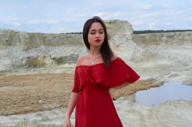 beautiful brunette girl in a bright red dress in the desert