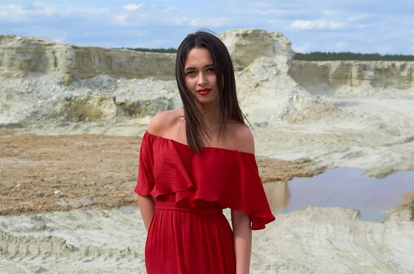 beautiful brunette girl in a bright red dress in the desert