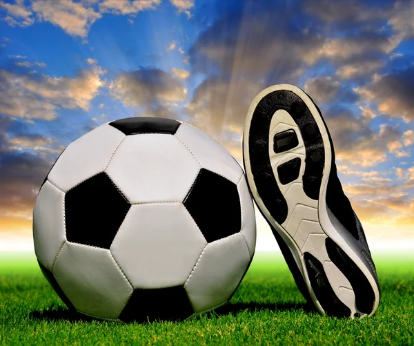 Soccer ball and shoes in grass — Stock Photo, Image