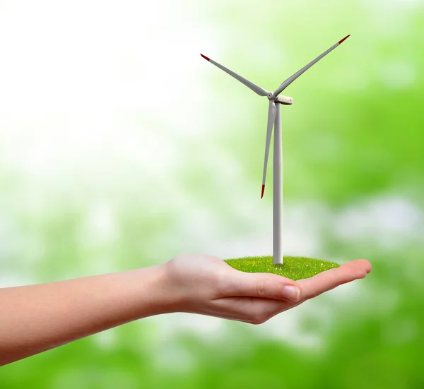 Ветряная турбина в руке на зеленом фоне — стоковое фото
