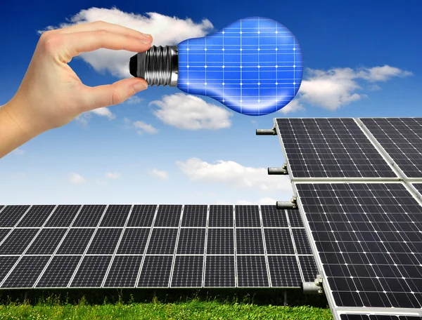 Solar panels with hand holding bulb — Stock Photo, Image
