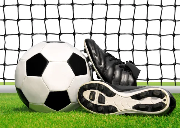 Soccer ball and shoes in grass — Stock Photo, Image