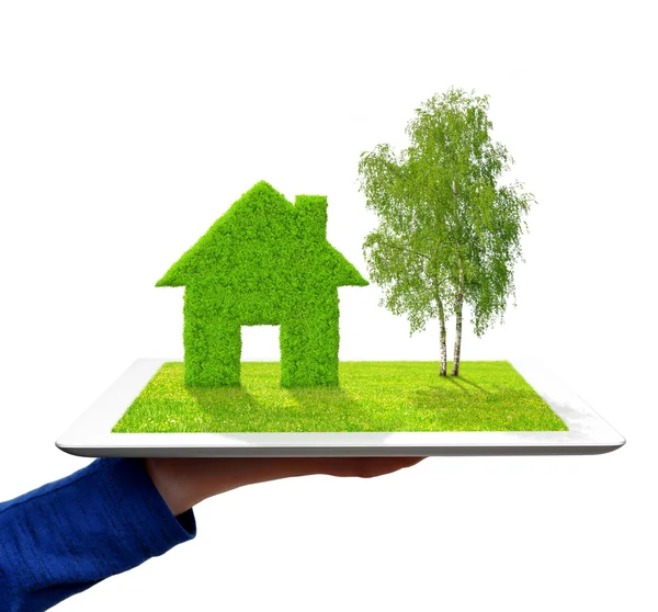 Mano sosteniendo una tableta con casa verde y árbol — Foto de Stock