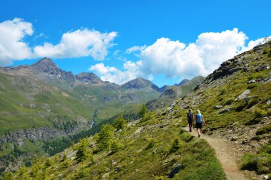 Gran Paradiso Ulusal Parkı 'nda yürüyüşçüler. Aosta Vadisi, İtalya. Güneşli bir günde güzel dağ manzarası.