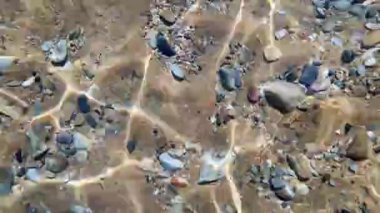 Kum ve taşlarla dalgalanan dipten denize bak. Sahildeki deniz tabanının sualtı görüntüsü..