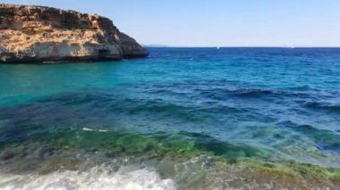 İspanya 'nın Mallorca adasında dalgalı dalgalar ve kayalık kıyılarla kristal berrak deniz manzarası.
