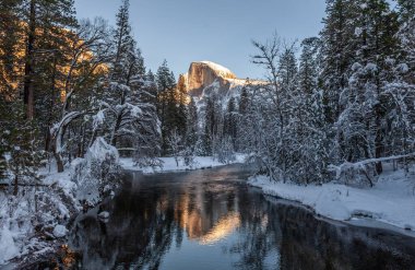 Yarım kubbenin zirvesi batan güneşin tam ışığında pişiyor. Merced nehrine yansıyor, parlak, karlı bir kış öğleden sonra, altın saat boyunca..