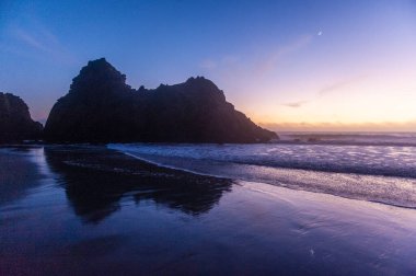 Gün batımında Pfeiffer Sahili 'ndeki anahtar deliği kemeri kayasının etkisi.