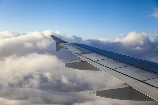 Bulutların üzerinde uçan bir uçağın kanat. uçak penceresinden görünümü — Stok fotoğraf