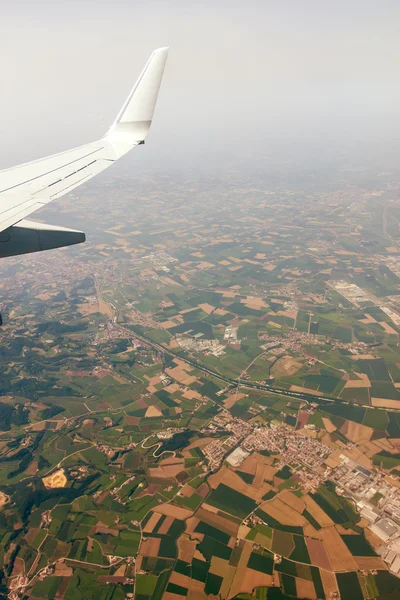 Blick auf den Boden und den Flügel eines Flugzeugfensters — Stockfoto