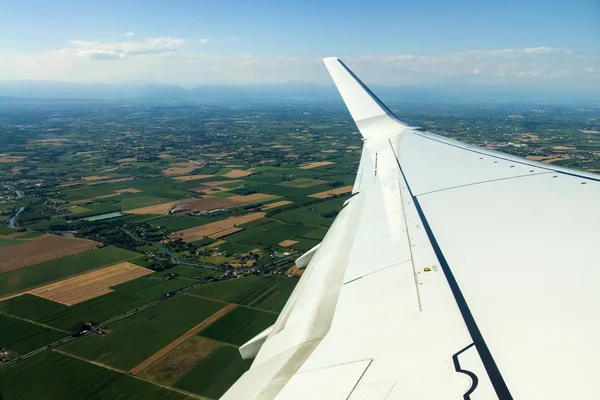 Vista do solo e da asa de uma janela de avião — Fotografia de Stock