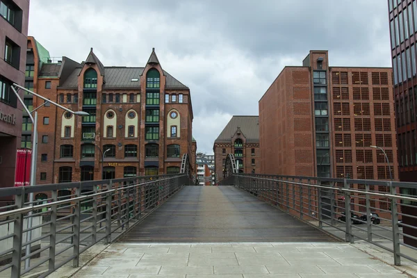 Hamburg, Německo, 19 února 2013. Most přes kanál a starých budov skladů a kanceláří v historickém městě v zatažené zimní počasí — Stock fotografie