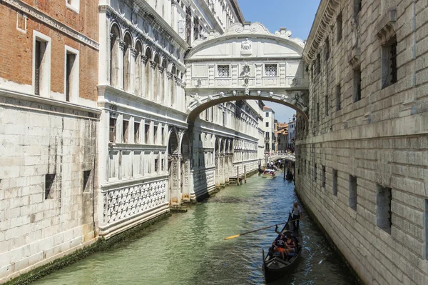 Venice, Italy, Tourists ride on a gondola through a channel — Stock Photo, Image