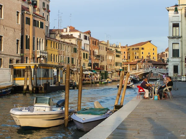 Venice, Italy, June 24, 2012 . Kind of a Venetian canal in the early evening . Tourists rest in a cafe on the shore — Stock Photo, Image