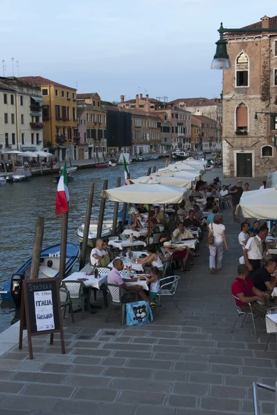 Venice, Italy, June 24, 2012 . Kind of a Venetian canal in the early evening . Tourists rest in a cafe on the shore — Stock Photo, Image