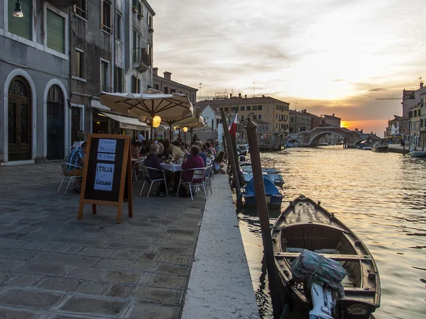 Venice, Italy, June 24, 2012 . Kind of a Venetian canal in the early evening . Tourists rest in a cafe on the shore — Stock Photo, Image