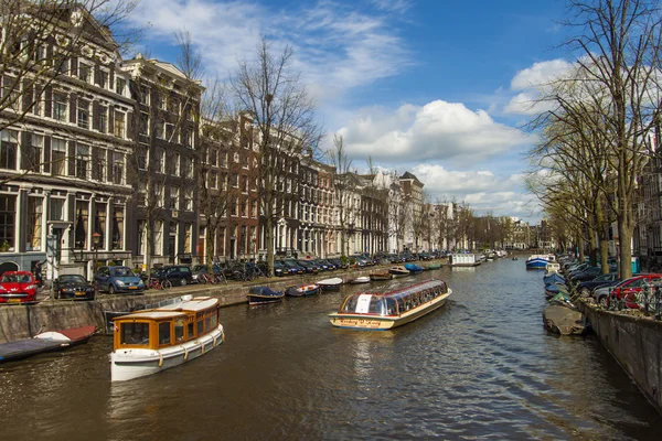 Amsterdam, Nederländerna den 14 april, 2012. nöje fartyget seglar genom kanalen i centrum av staden förbi de gamla hus av traditionell arkitektur — Stockfoto