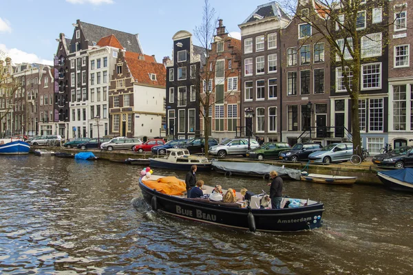 Amsterdam, The Netherlands April 14, 2012 . Pleasure ship sails through the channel in the center of town past the old houses of traditional architecture — Stock Photo, Image