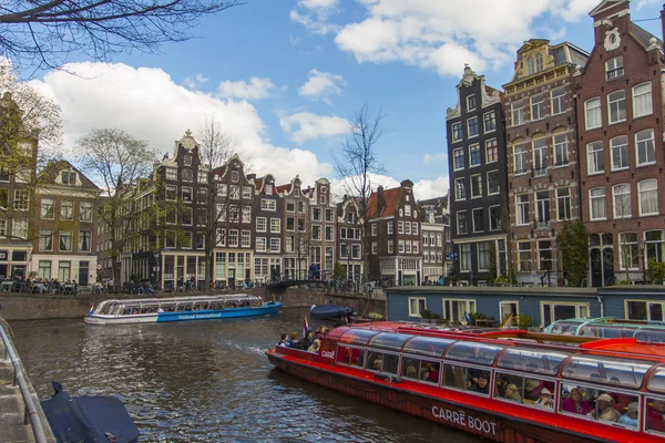 Ámsterdam, Países Bajos 14 de abril de 2012. Buque de placer navega a través del canal en el centro de la ciudad más allá de las antiguas casas de arquitectura tradicional — Foto de Stock