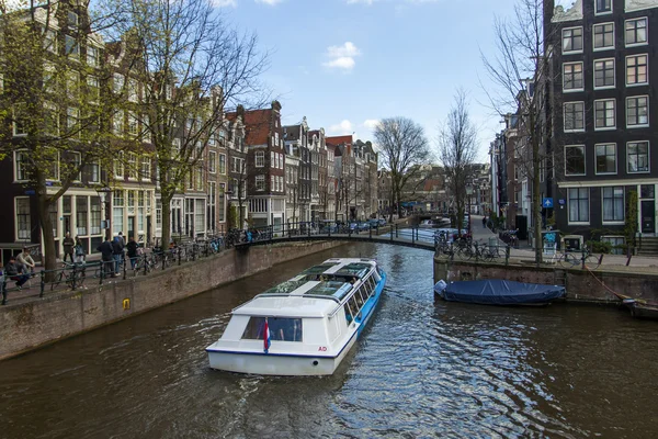 Амстердам, Нидерланды 14 апреля 2012 года. Корабль удовольствия плывет через канал в центре города мимо старых домов традиционной архитектуры — стоковое фото