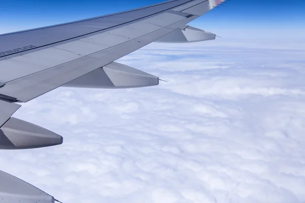Pencere görünümünden uçak kanatlarının ve bulutların yoğun bir yatak üzerinde — Stok fotoğraf