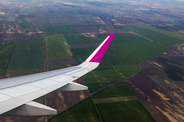 Blick aus dem Fenster des fliegenden Flugzeugs auf Erde und Wolken — Stockfoto