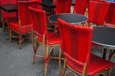 Summer outdoor café in a European city, tables and bright red wicker chairs