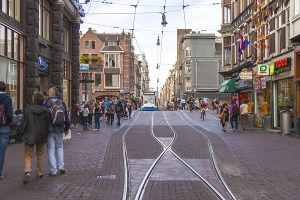 Amsterdam, Netherlands, on July 7, 2014. Tourists and citizens go on the narrow brisk street with tram ways — Stock Photo, Image