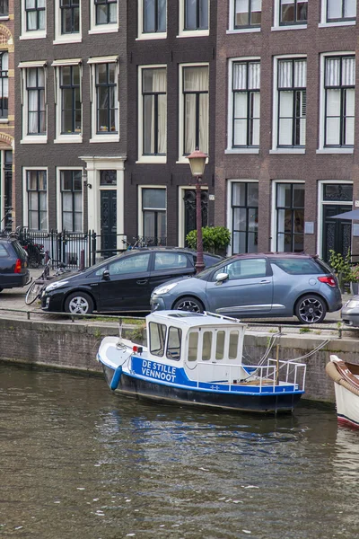 Amsterdam, Nederländerna, den 7 juli 2014. typiska urban Visa med hus på stranden av kanalen och den gamla stenbron — Stockfoto