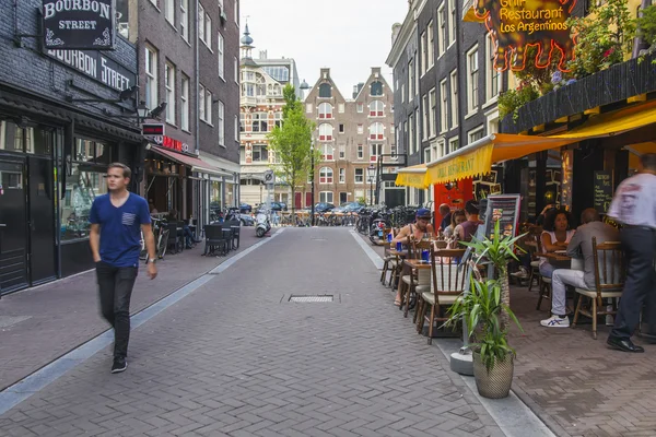 Amsterdam, Netherlands, on July 7, 2014. Tourists and citizens sit at cafe little tables on the street — Stock Photo, Image