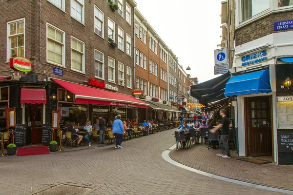 Amsterdam, Nizozemsko, na 7 červenci 2014. turisté a občané sedět v kavárně málo stolů na ulici — Stock fotografie