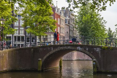 Amsterdam, Hollanda, 7 Temmuz 2014 tarihinde. Banka kanalı ve eski taş köprü evleriyle tipik kentsel görünümü