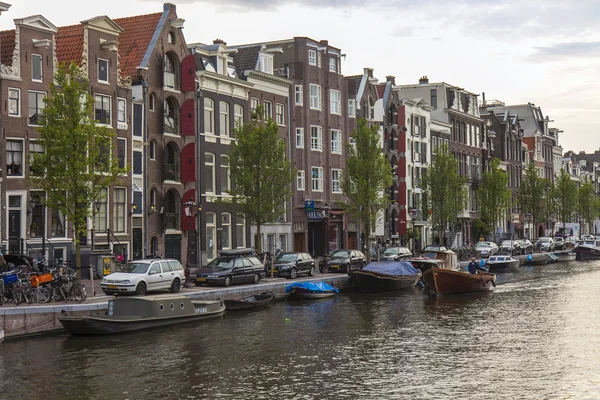 Ámsterdam, Países Bajos, 7 de julio de 2014. Típica vista urbana con casas a orillas del canal y el viejo puente de piedra — Foto de Stock