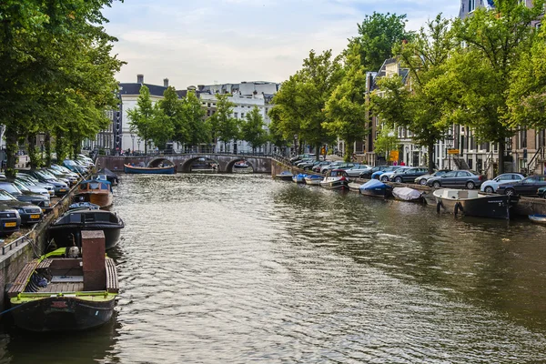 Amsterdam, Pays-Bas, le 7 juillet 2014. Vue urbaine typique avec des maisons sur la rive du canal et le vieux pont en pierre — Photo