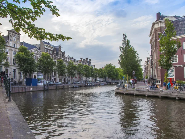 Ámsterdam, Países Bajos, 7 de julio de 2014. Típica vista urbana con casas a orillas del canal y el viejo puente de piedra — Foto de Stock