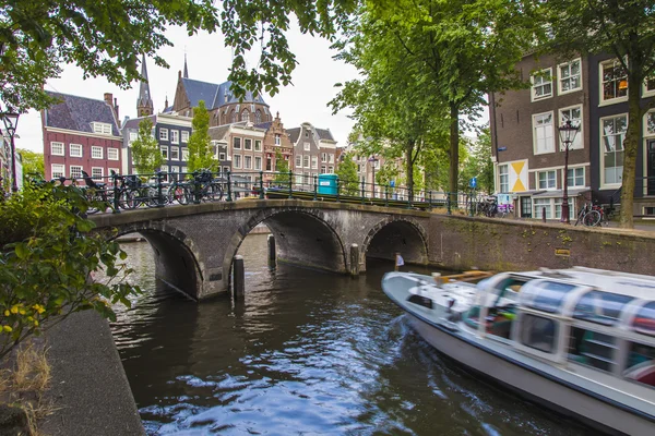 Amsterdam, Nederland, op 7 juli 2014. typisch stedelijke weergave met huizen aan de oever van het kanaal en de oude stenen brug — Stockfoto