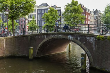 Amsterdam, Hollanda, 7 Temmuz 2014 tarihinde. Banka kanalı ve eski taş köprü evleriyle tipik kentsel görünümü