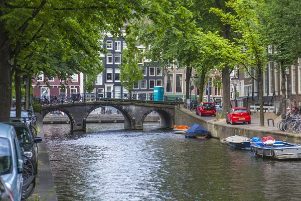 Ámsterdam, Países Bajos, 7 de julio de 2014. Típica vista urbana con casas a orillas del canal y el viejo puente de piedra — Foto de Stock