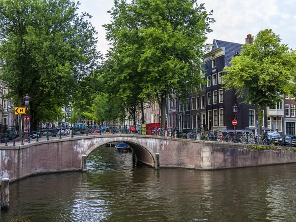 Amsterdam, Nederländerna, den 7 juli 2014. typiska urban Visa med hus på stranden av kanalen och den gamla stenbron — Stockfoto