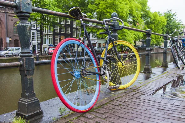 Amsterdam, Hollanda, üzerinde 10 Temmuz 2014. Bisiklet kanal kıyısında şehrin cadde üzerinde park edilmiş — Stok fotoğraf